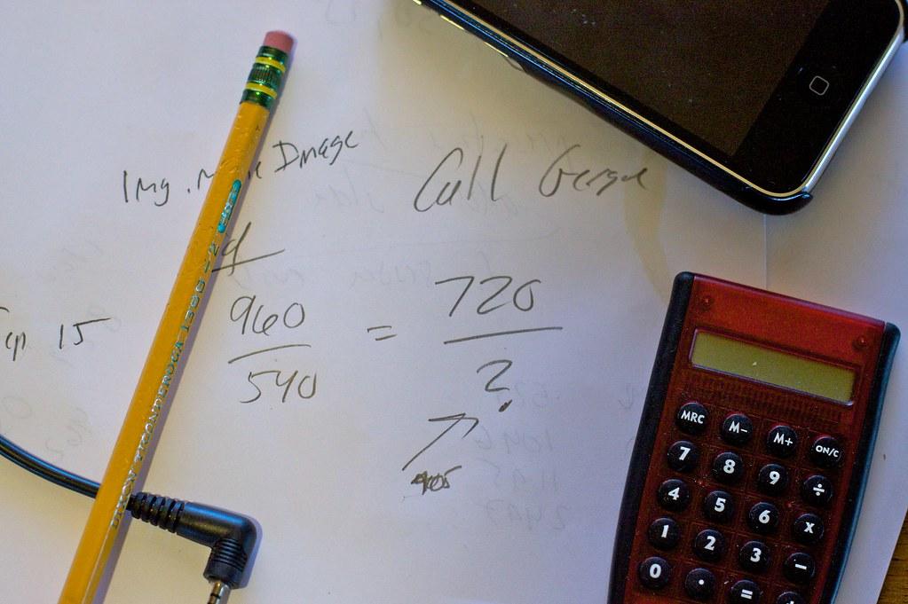 Calculadora e anotações de cálculos financeiros sobre papel